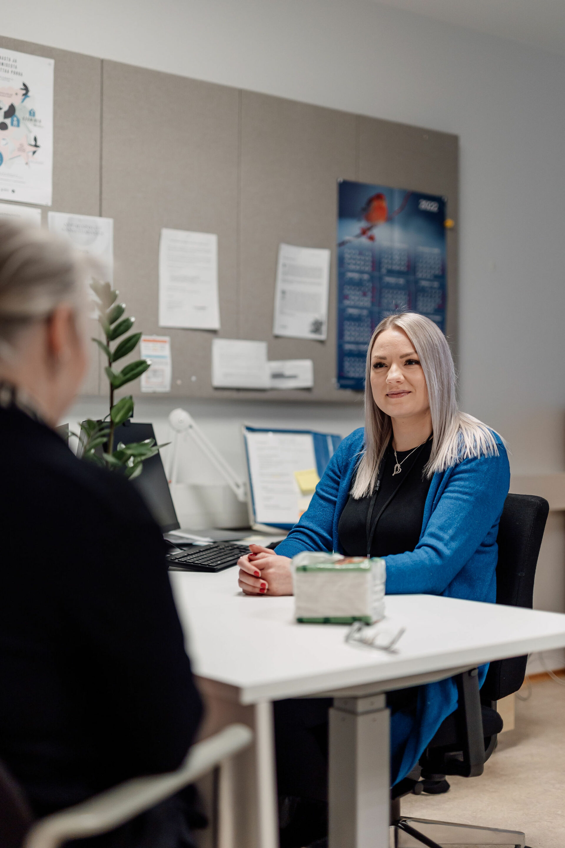 Asiakaspalveluhenkilö ja asiakas istuvat pöydän äärellä.