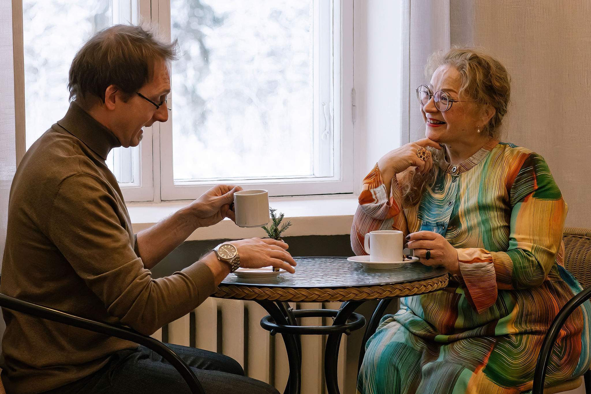 Kaksi henkilöä istuvat kahvilla, sosiaalinen tilanne.