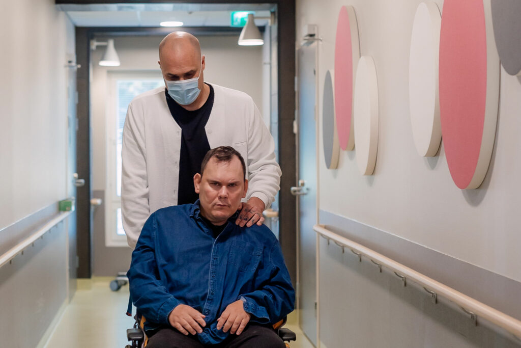 Samuel Rantala työntää Petri Haaron pyörätuolia Pääkujan palveluyksikön käytävällä.