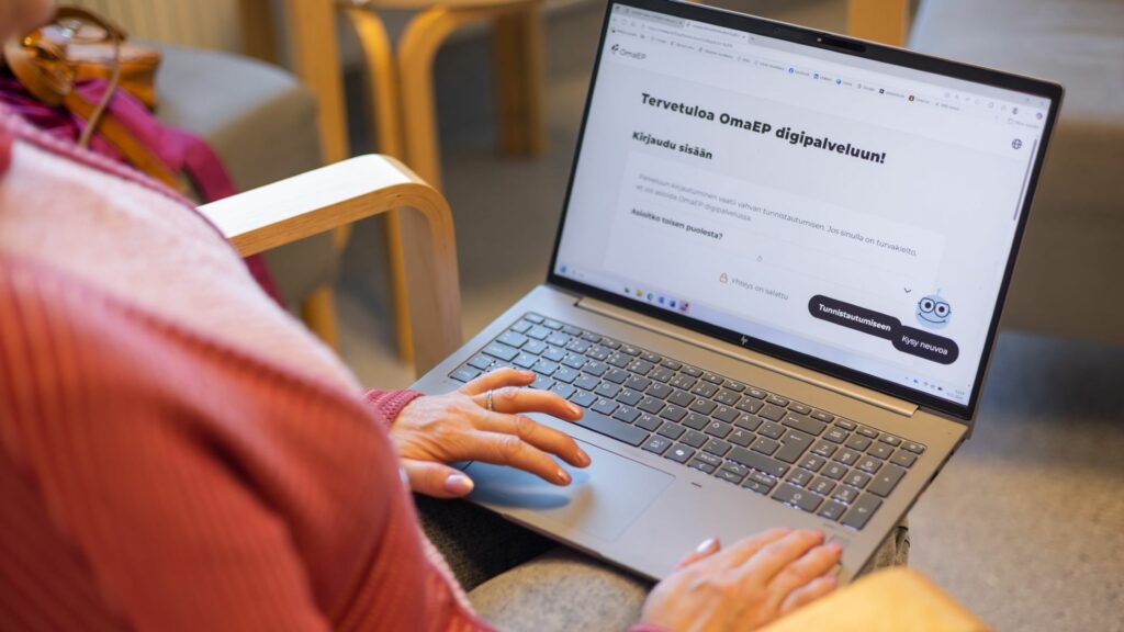 Nainen katsoo kannettavan tietokoneen näyttöä. Näytöllä näkyy OmaEP digipalvelun aloitussivu: Tervetuloa OmaEP digipalveluun. Kirjaudu sisään.