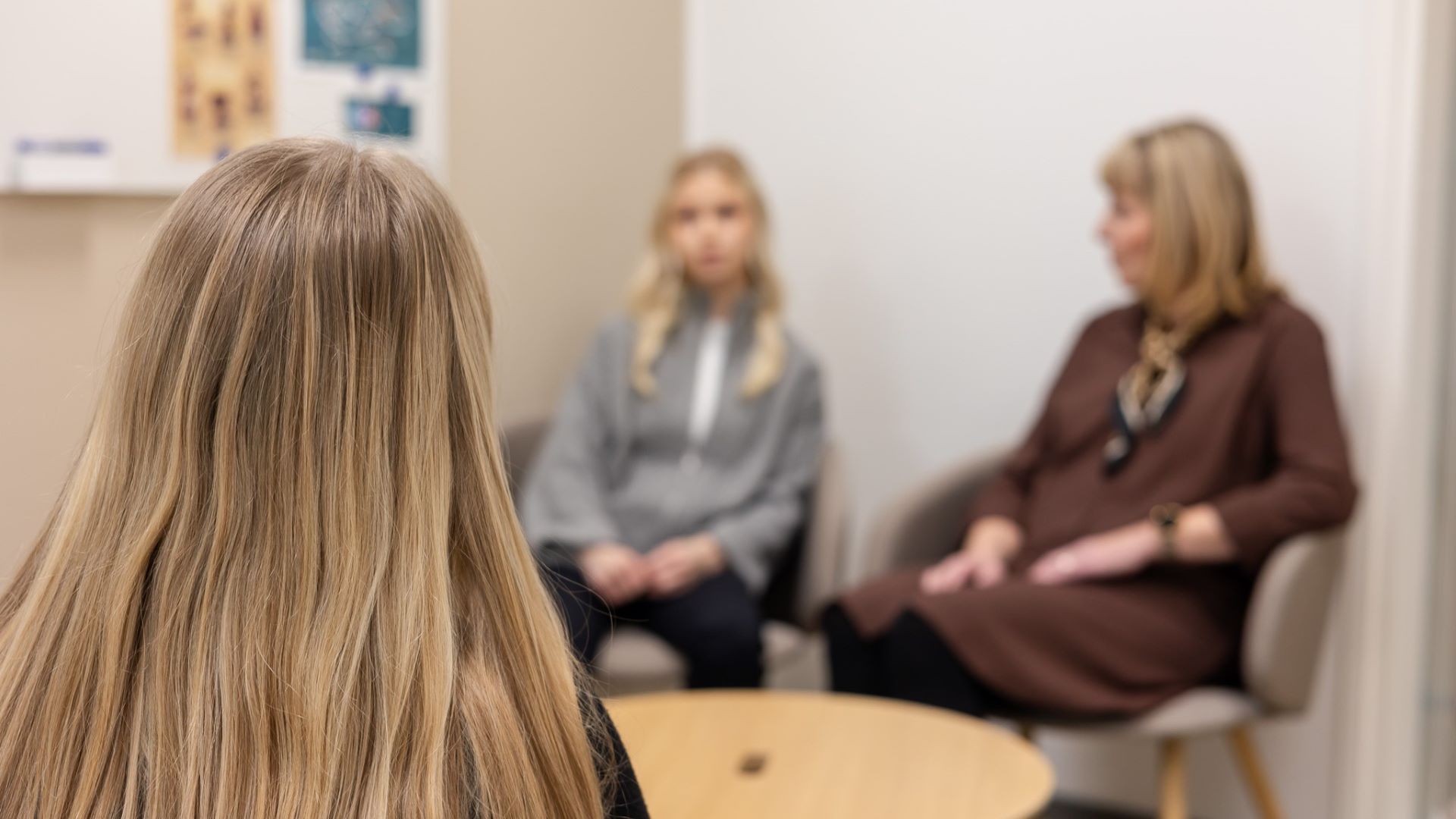 Kolme naista keskustelevat pyöreän pöydän äärellä.